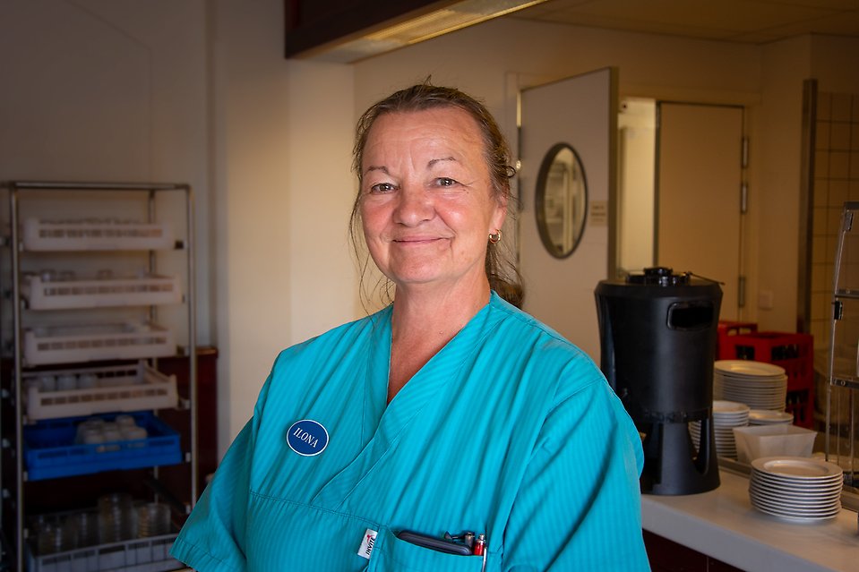 Bild på Ilona, undersköterska och aktivitetsansvarig på Nyhamnsgården. Hon kollar in i kameran och ler.